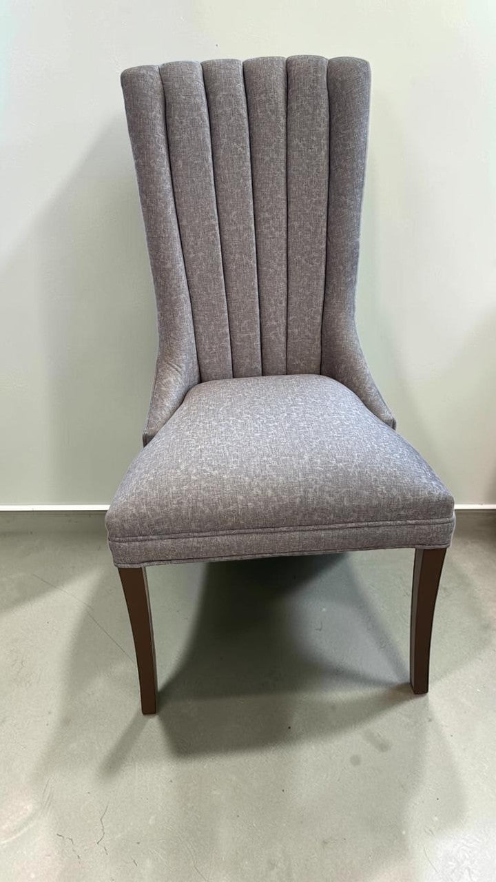 Silla Dusseldorf de CASA GARRIDO Muebles con tapizado gris, respaldo acanalado ergonómico y patas de madera oscura.