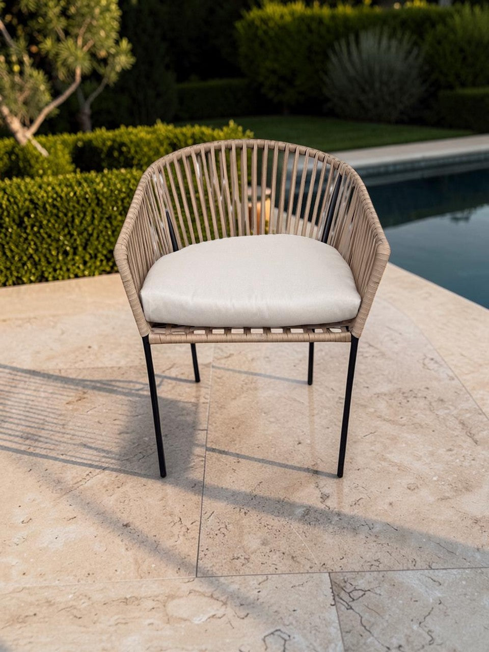 Silla Carreña de CASA GARRIDO Muebles con estructura de metal negro, tejido de mimbre sintético y cojín blanco.