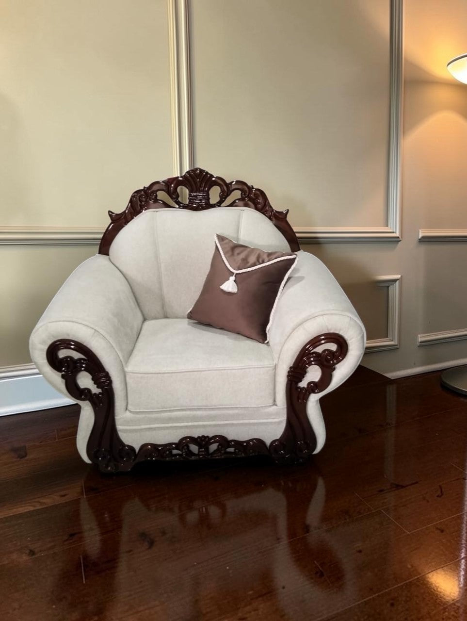 Sillón Modelo Carey de CASA GARRIDO Muebles con tapizado beige, estructura de madera tallada oscura y cojín marrón.