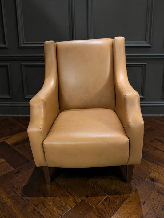 Sillón Kabul de CASA GARRIDO Muebles tapizado en cuero color beige con diseño de respaldo alto y patas de madera