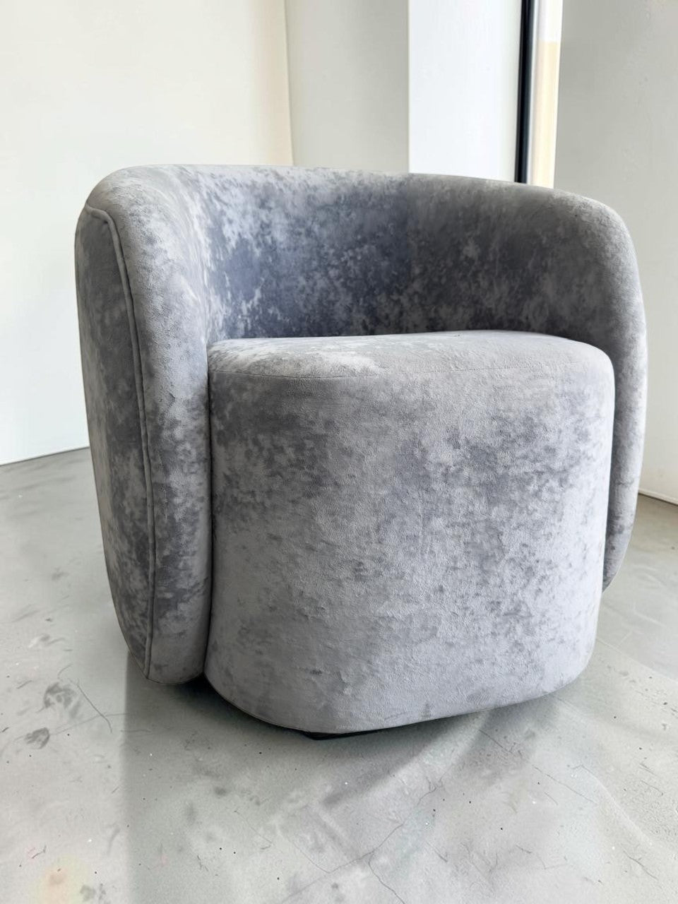 Sillón Kabul de CASA GARRIDO Muebles en tela gris aterciopelada con diseño curvo contemporáneo y estructura robusta.
