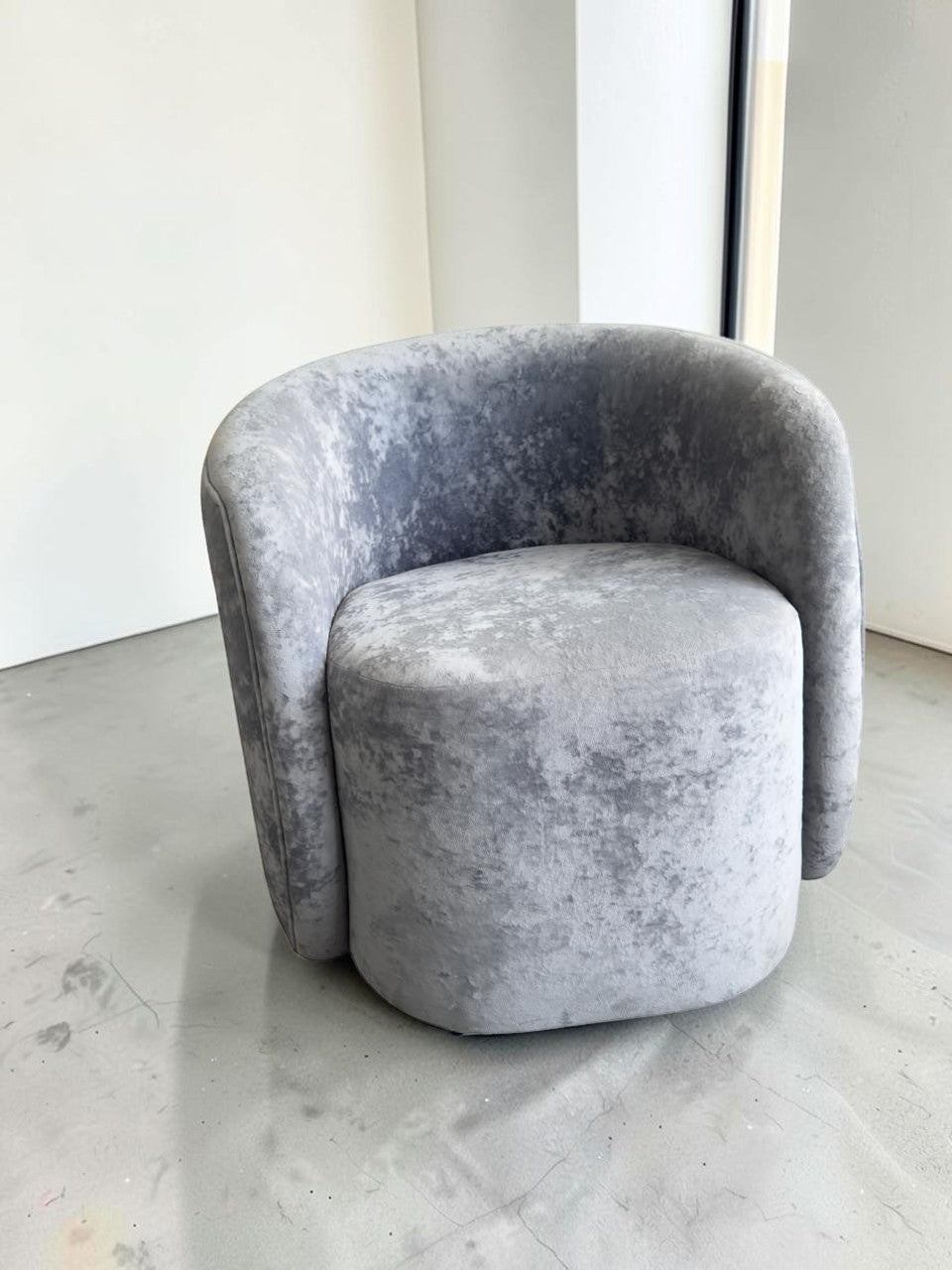 Sillón Kabul de CASA GARRIDO Muebles con diseño curvo contemporáneo y tapizado de terciopelo gris texturizado.