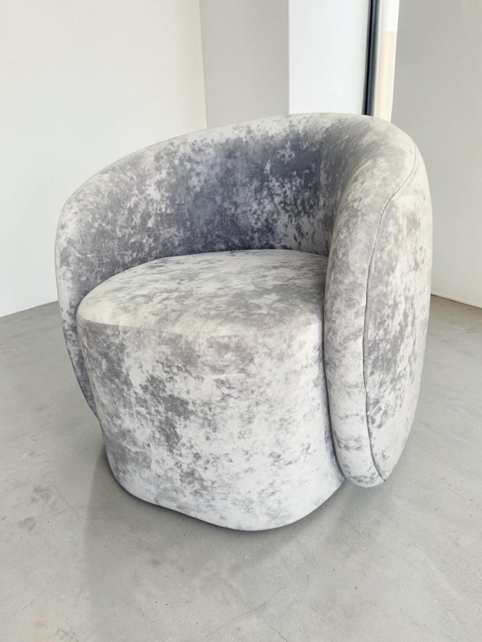 Sillón Kabul de CASA GARRIDO Muebles con diseño curvo contemporáneo y tapizado de terciopelo gris texturizado.