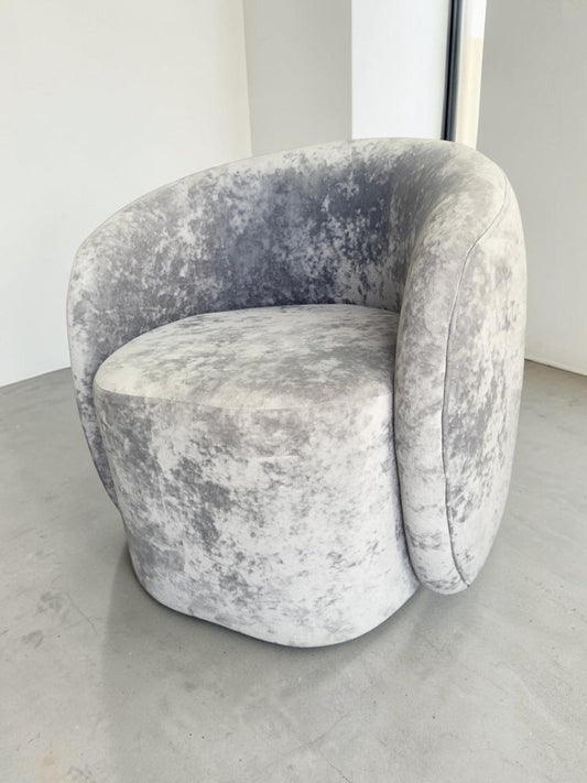 Sillón Kabul de CASA GARRIDO Muebles con diseño curvo contemporáneo y tapizado de terciopelo gris texturizado.