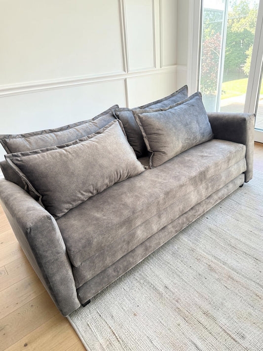 Sofá cama Bangkok de CASA GARRIDO Muebles en tela gris aterciopelada con cojines de respaldo, diseño moderno y elegante.