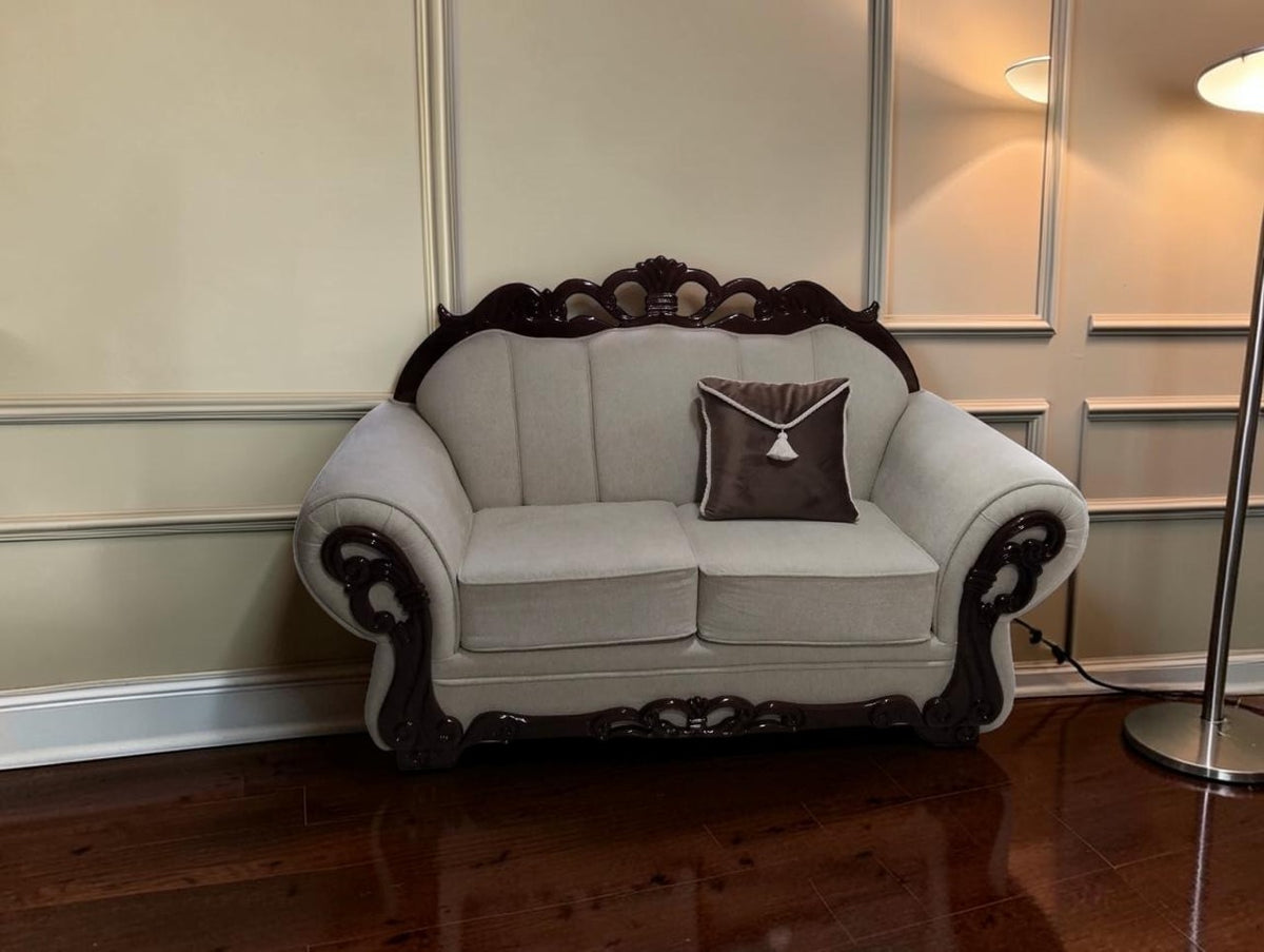Sofá de dos plazas CASA GARRIDO Muebles modelo Carey con tapizado beige, estructura de madera oscura y cojín marrón.