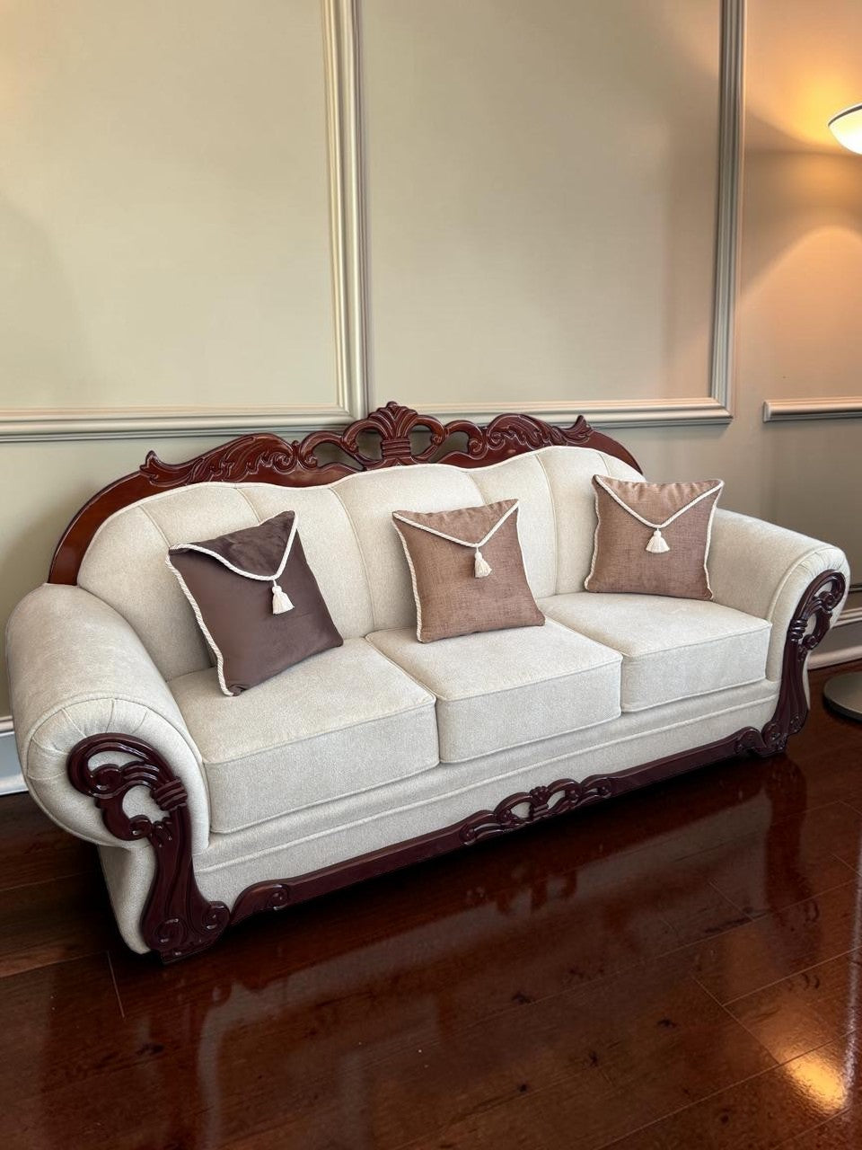 Sofá Modelo Carey de CASA GARRIDO Muebles con tapizado beige, estructura de madera tallada y cojines decorativos.