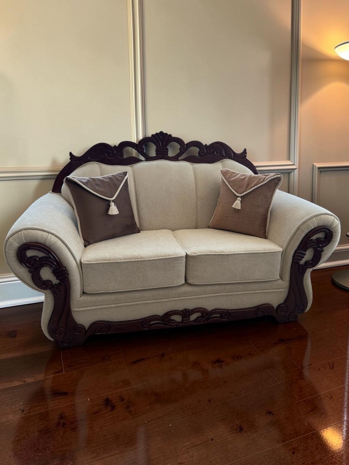 Sofá de dos plazas CASA GARRIDO Muebles con tapicería beige, estructura de madera oscura tallada y cojines decorativos